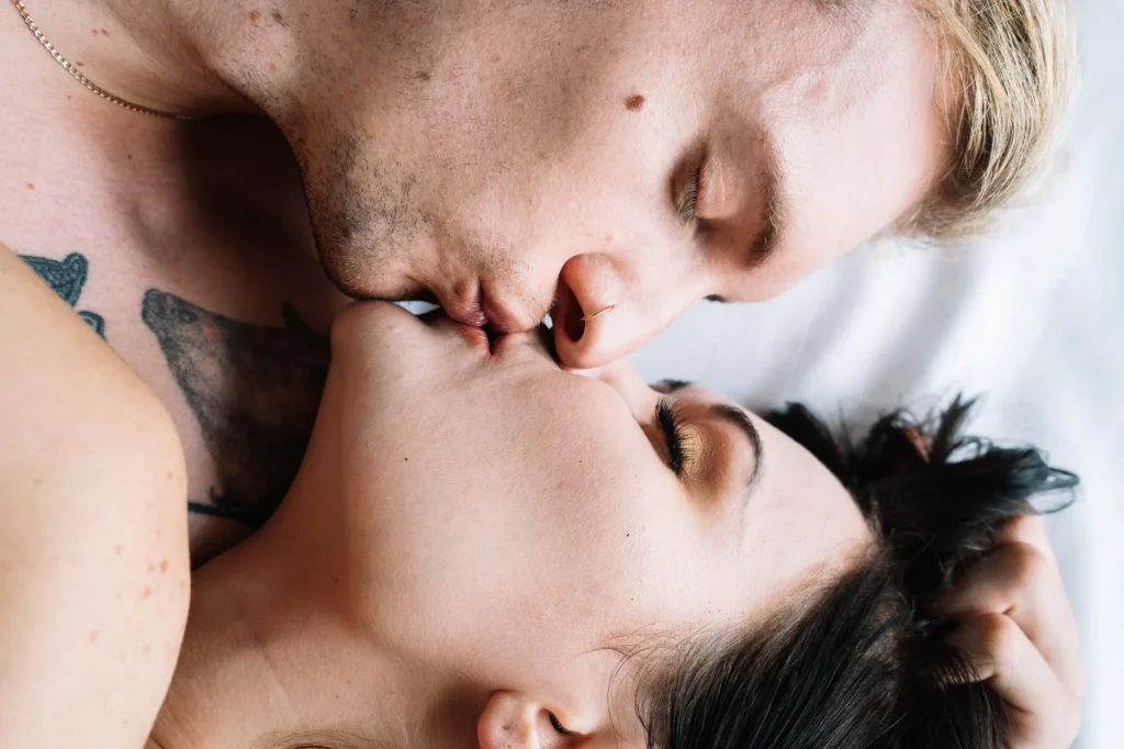 Casal se beijando intimamente em uma cama, destacando amor e conexão