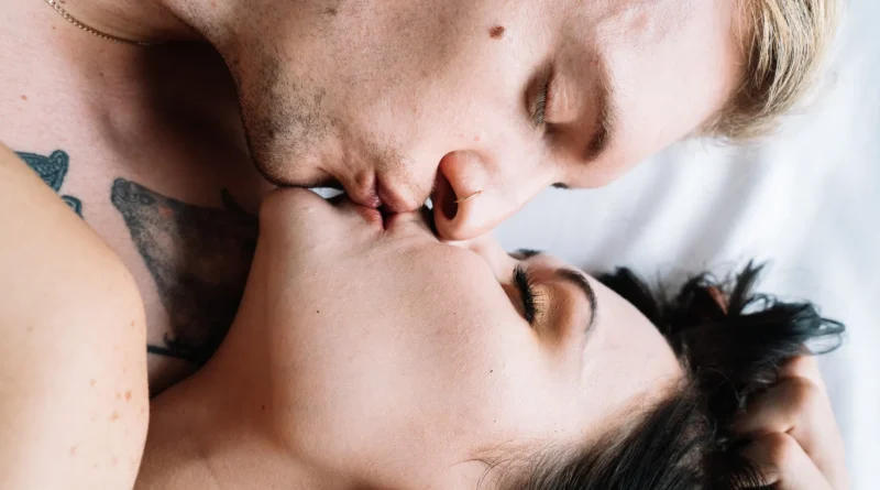 Casal se beijando intimamente em uma cama, destacando amor e conexão