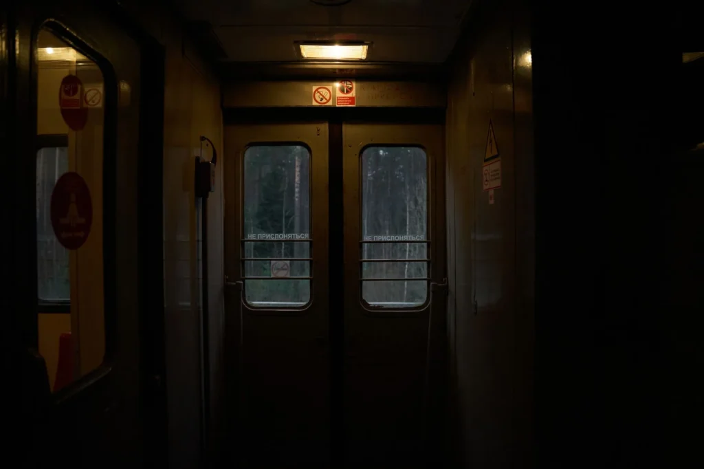 Interior de um trem noturno com bancos azuis vazios e luz amarelada entrando pela janela
