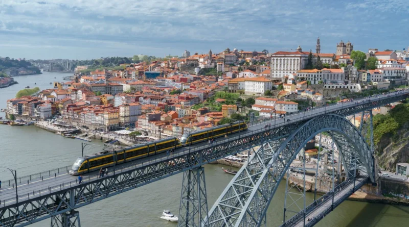 Dois convidados adultos conversando timidamente numa mesa de casamento ao entardecer, com as vinhas do Douro ao fundo