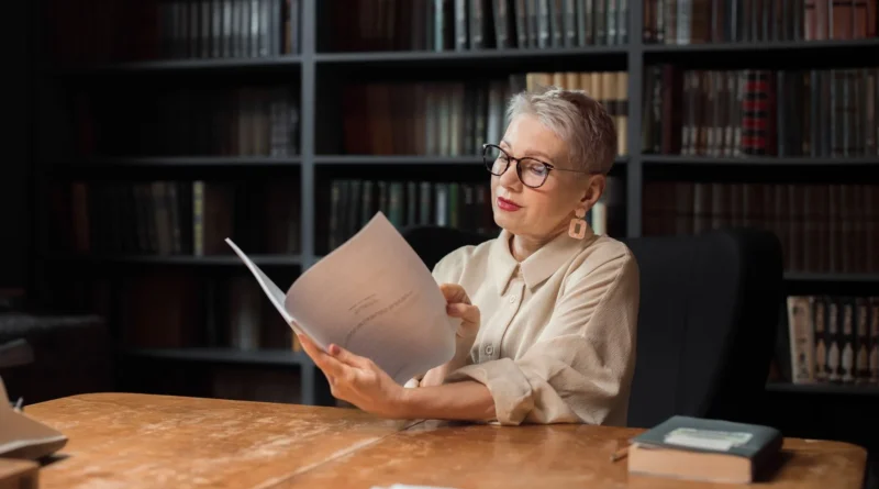 Duas pessoas adultas leem um manuscrito à luz quente de uma biblioteca à noite