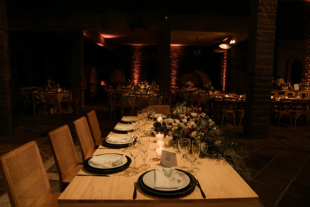 Recepção de casamento à noite com luzes quentes e copos de vinho do Porto sobre a mesa