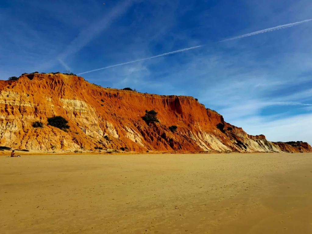 Pôr do sol dourado sobre as falésias e o mar calmo do Algarve, em Lagos, criando um cenário romântico de fim de tarde sem pessoas