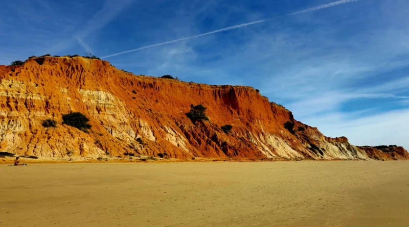 Pôr do sol dourado sobre as falésias e o mar calmo do Algarve, em Lagos, criando um cenário romântico de fim de tarde sem pessoas