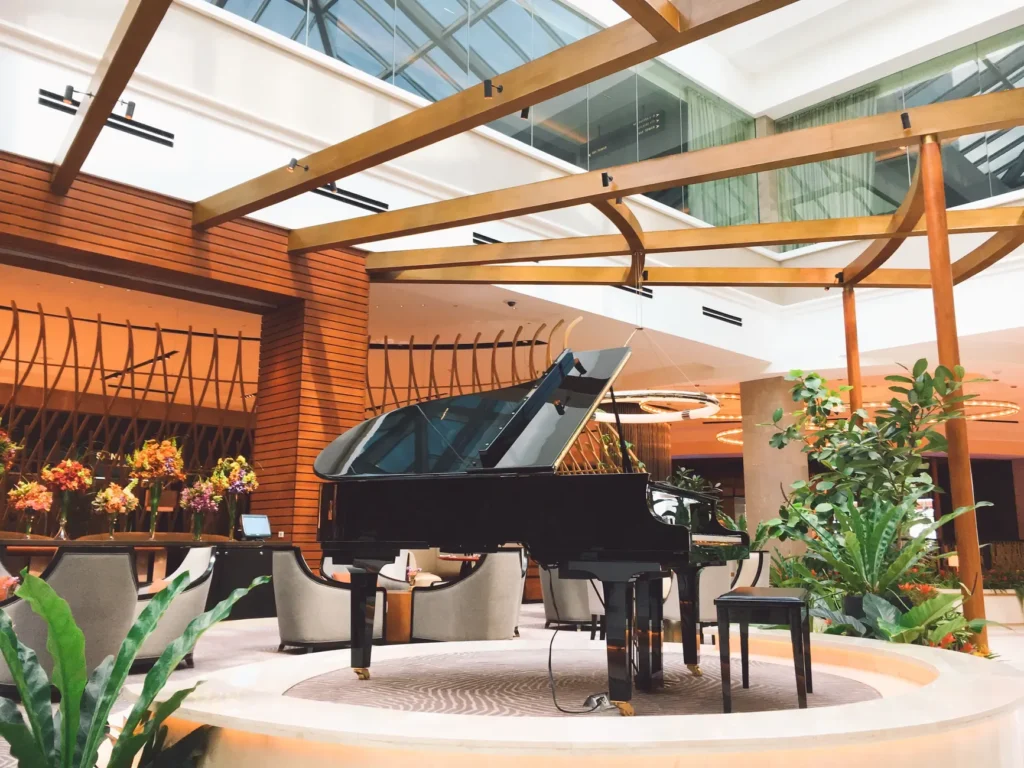 Piano de cauda num salão de hotel à meia-luz, com a chuva escorrendo nas janelas voltadas para o rio