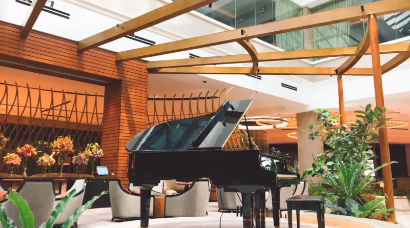 Piano de cauda num salão de hotel à meia-luz, com a chuva escorrendo nas janelas voltadas para o rio