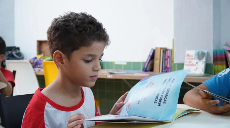 Dois adultos leem livros juntos à mesa sob a luz quente de um abajur